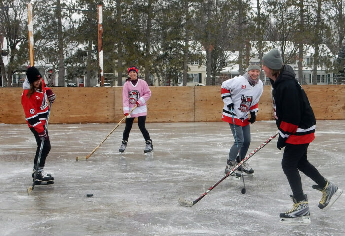 Four skaters playing hockey on the Manor Park outdoor rink.