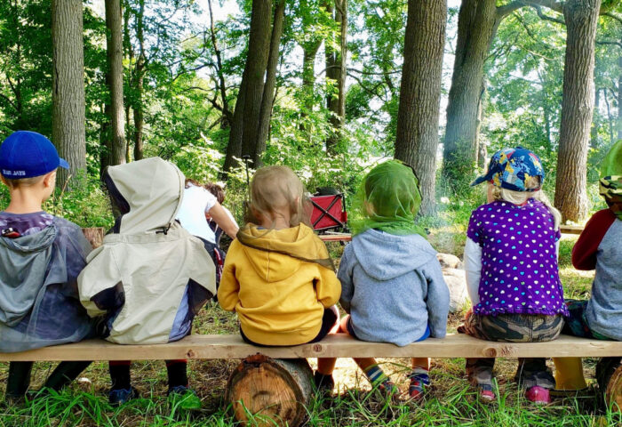 Children with their backs to us sitting on a bench.