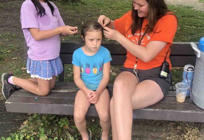 At MPCC summer camp, Sam Proulx has her hair braided by fellow camper Maki Kobayashi, left, and counsellor Anna Jack. Photo supplied by MPCC