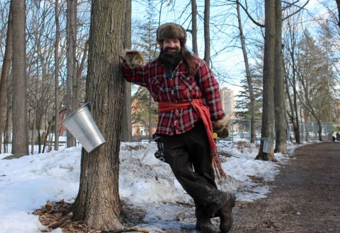 In this photo from the 2021 Vanier sugar shack tree-tapping, Mario Bélisle, the Vanier Museopark’s program manager and tapping facilitator, poses in habitant dress and with a power drill hanging off his belt. Photo: Marie-Frédérique Caron