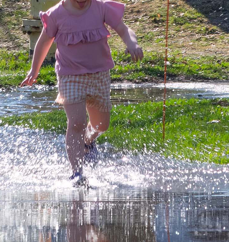 A photo of a child running through a puddle to illustrate Douglas Cornish column about the significace of neighbourhood streets. Photo is by Doug Banks