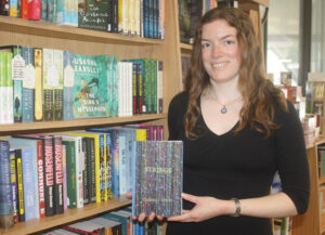 Books on Beechwood store manager Hilary Porter holds a copy of Strings, a first novel by Manor Park author Christie J. Oliver. PHOTO: RYLAND COYNE