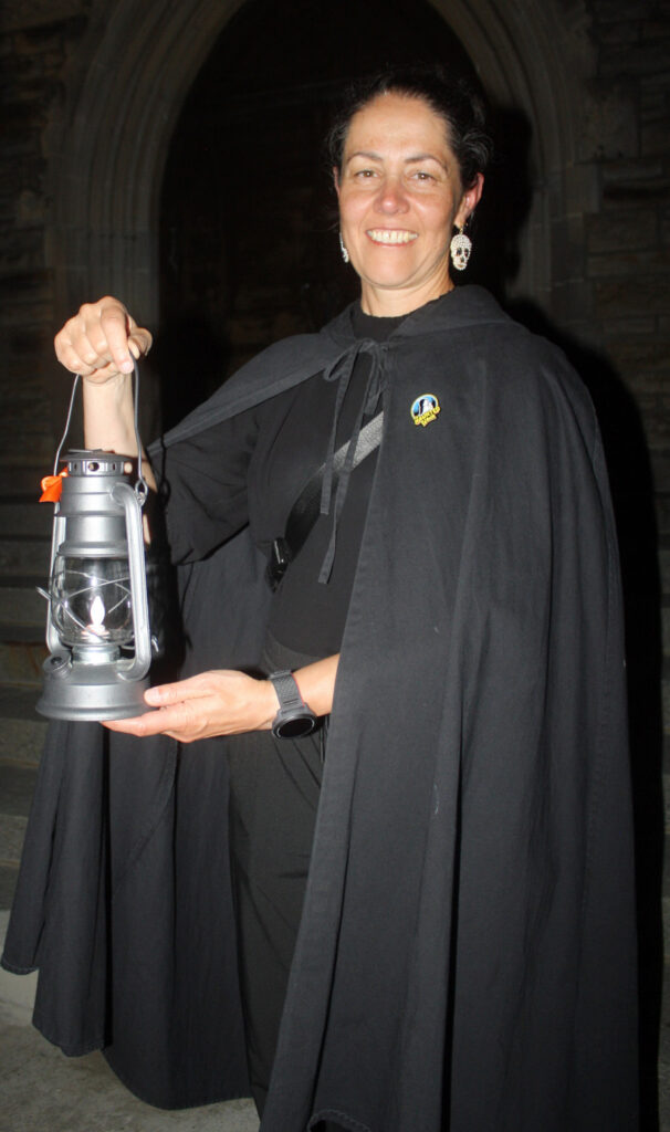 Haunted Walk guide Kathryn Lyons holds up a lantern to help guide visitors through the Beechwood Cemetery. PHOTO: Ryland Coyne