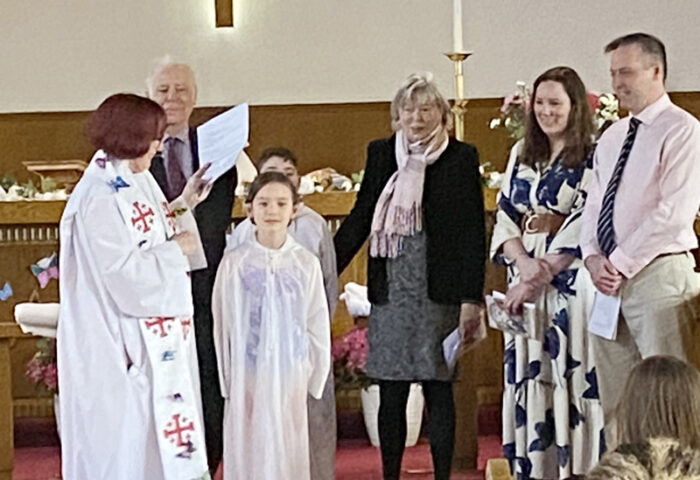 Reverend Susan Lewis (left) prepares to baptize young Beatrice Trudeau (centre front) and her brother Niall (back) during the Easter service. Looking on (left to right) are the children's grandparents Brian and Mary Wolff, and parents Clara and Mike Trudeau. PHOTO: DIANA POITRAS
